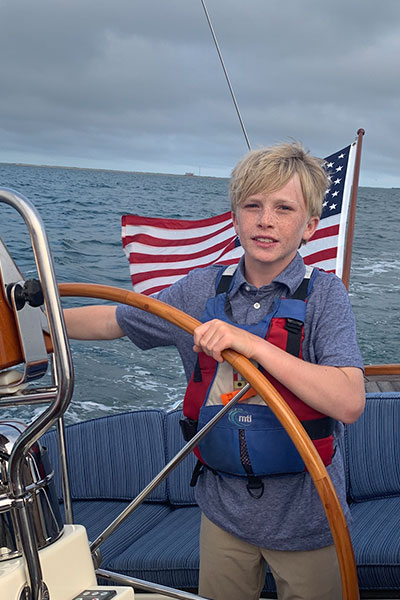 boy manning the wheel of a sailboat