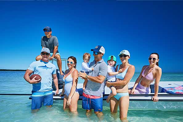 capt. jesse and family standing in the water by a boat