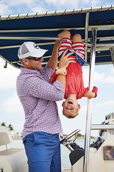 brett ekblom on a boat holding his son upside down